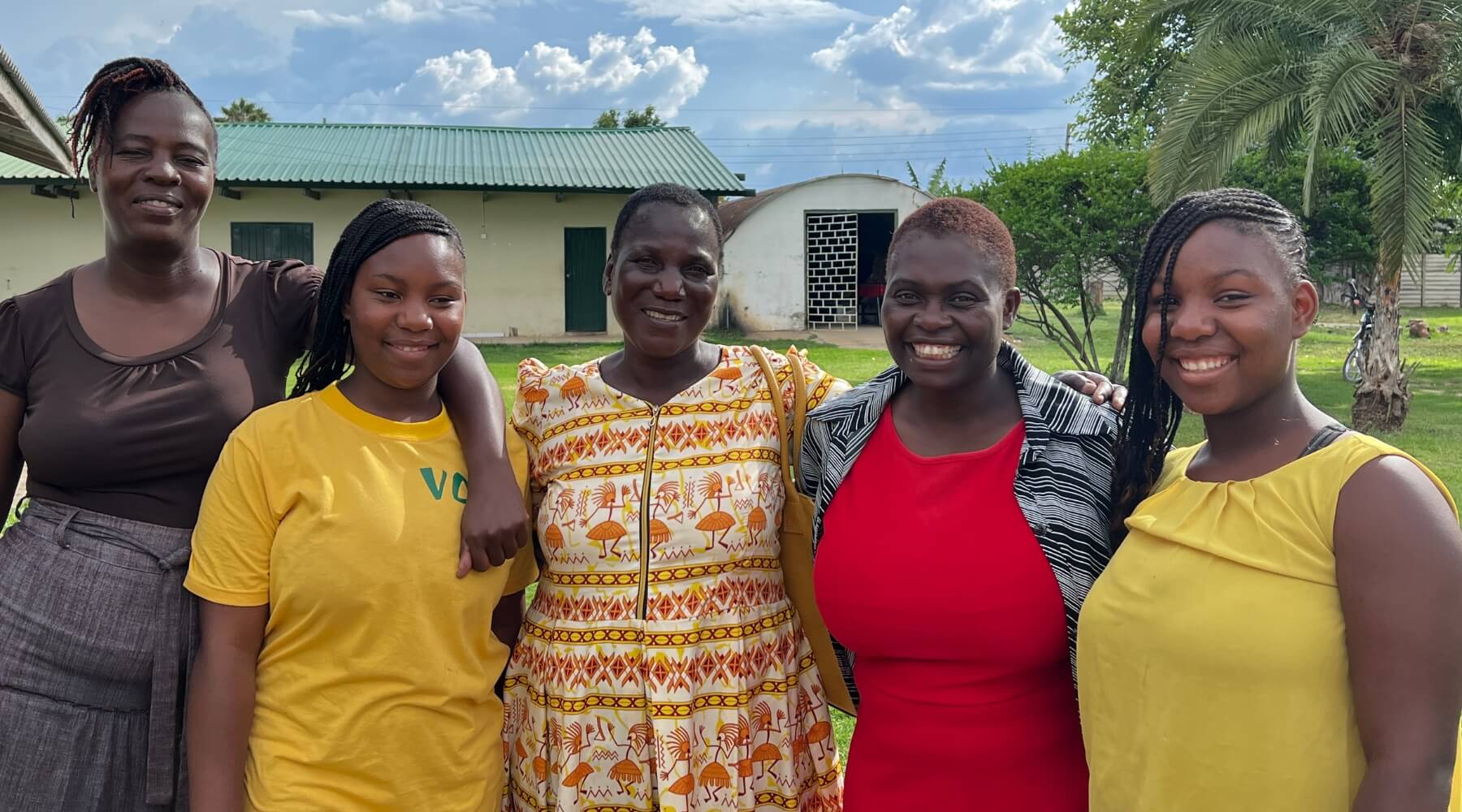 three adults with two young adults, smiling at the camera
