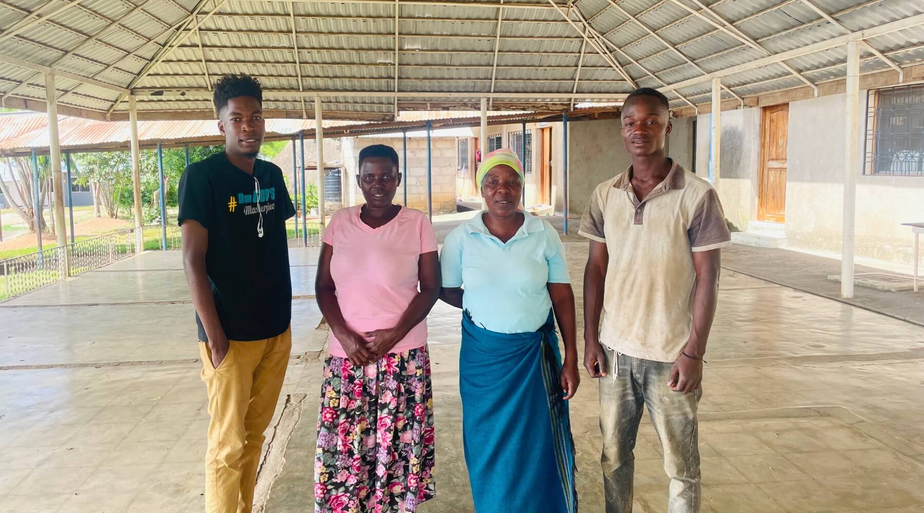 Four adults standing looking at the camera. The two on either side are young adults.