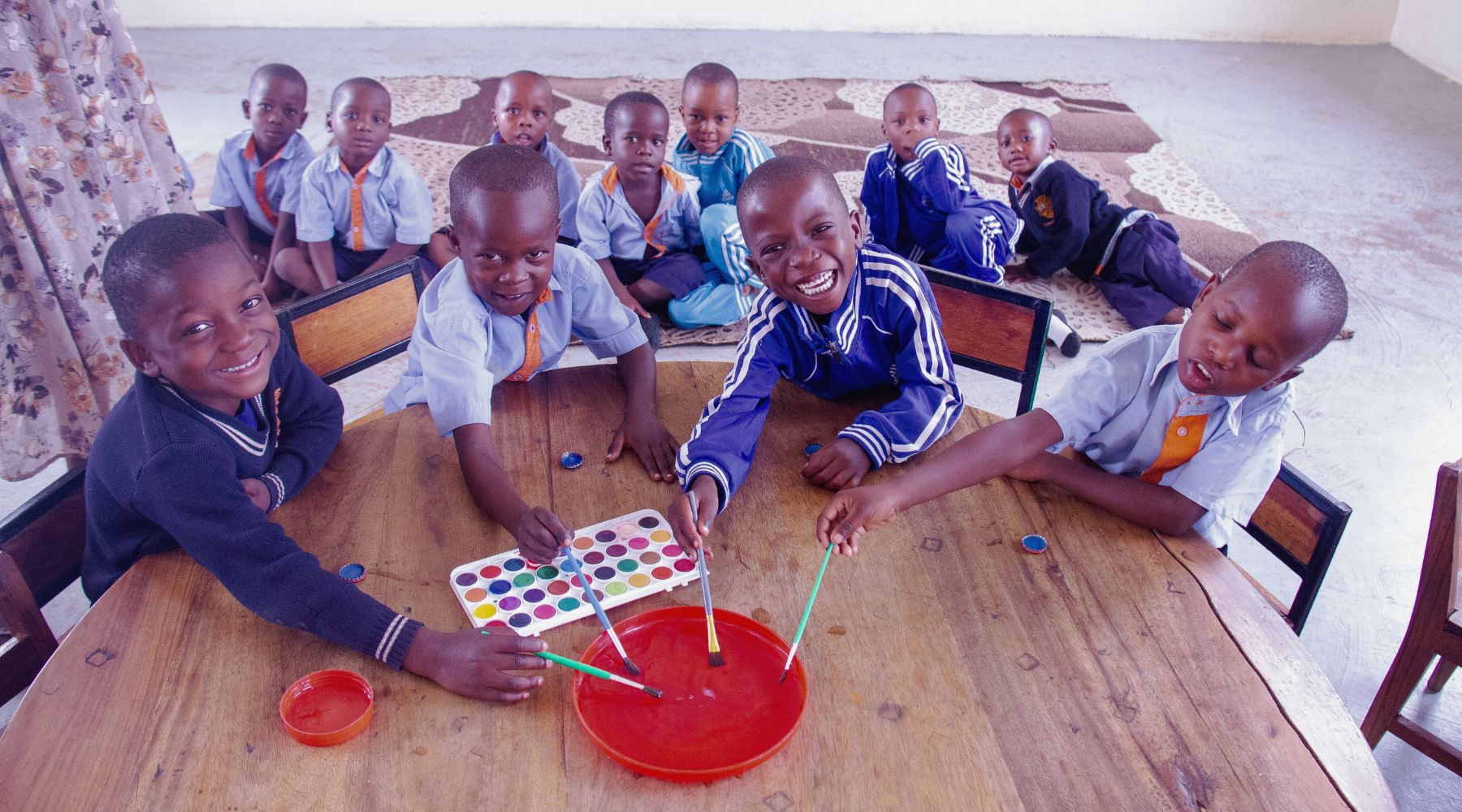 2024.10.28-bulale four students sitting at a table holding paintbrushes and smiling at the camera