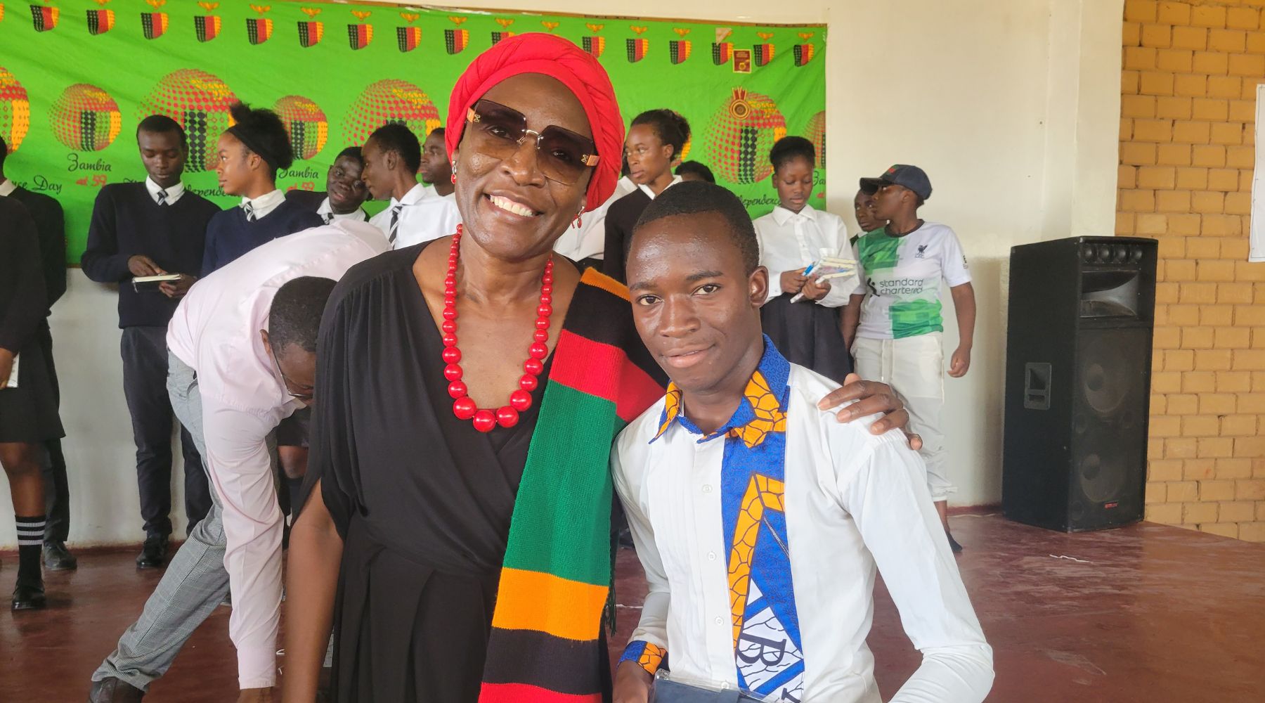 2024.10.28-kitwe A woman standing with her arm around a student, wearing a Zambian flag scarf