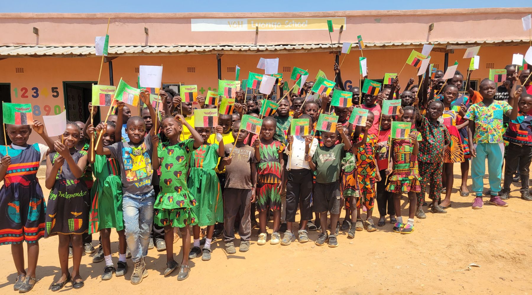 2024.10.28-luongo A large group of kids holding up Zambian flags and smiling