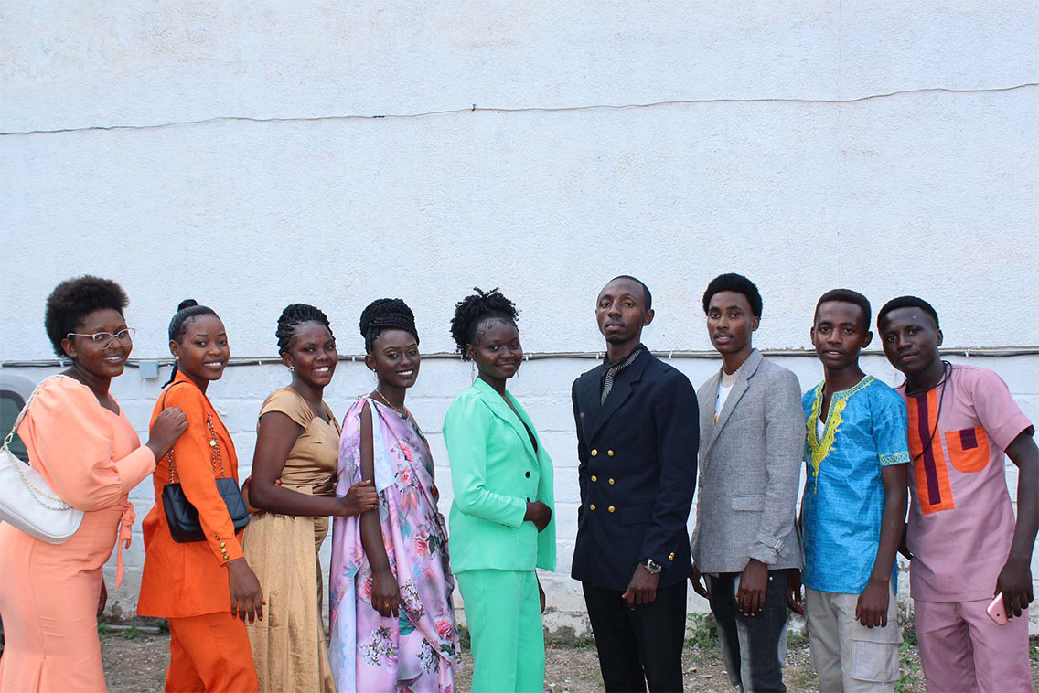 A group of young people standing in a line, smiling at the camera.