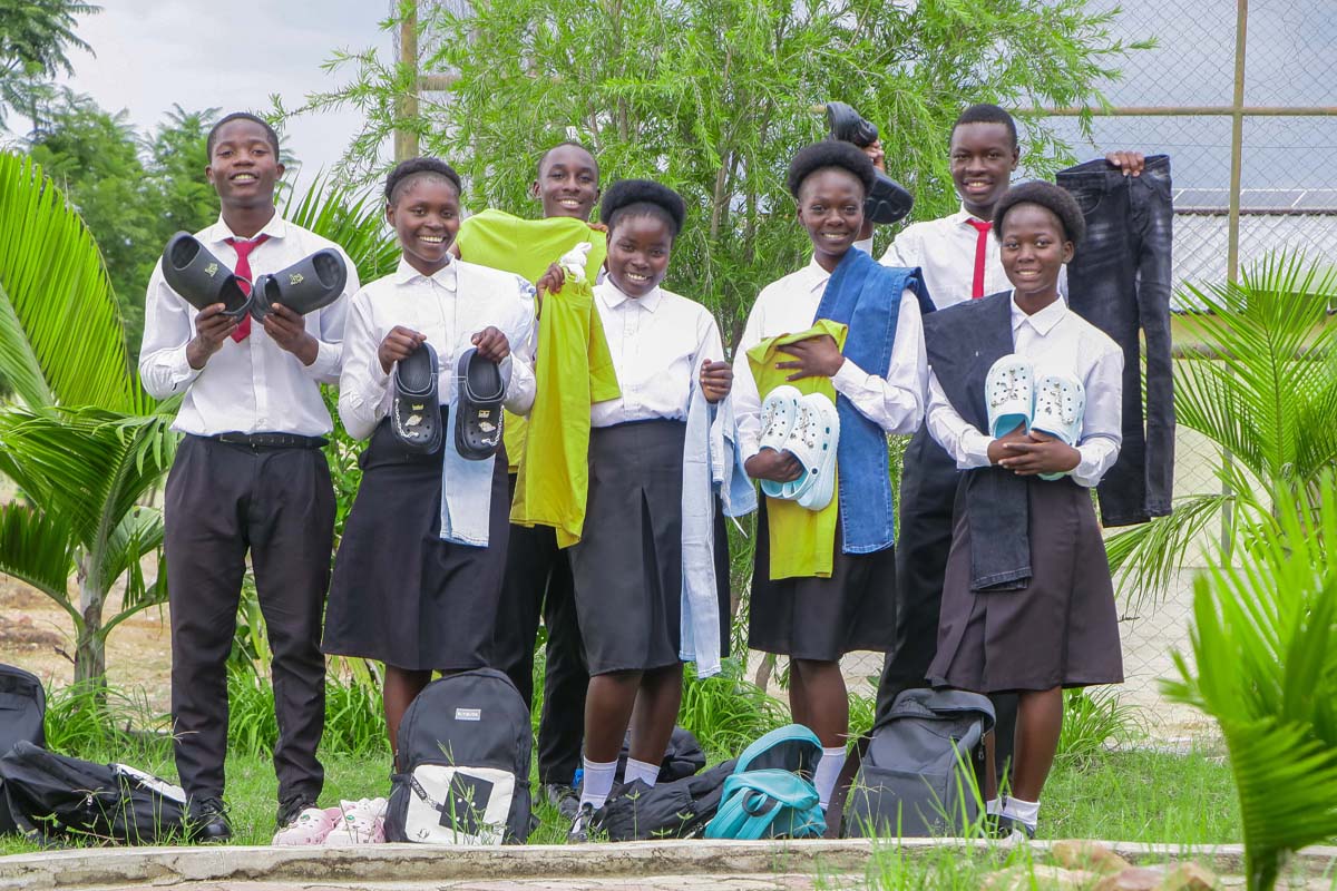 Youth holding gifts and clothes, smiling at the camera