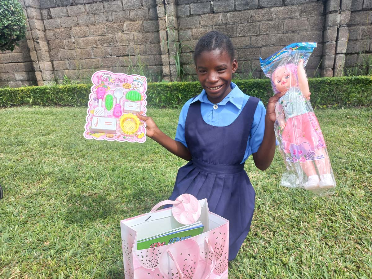 Child holding up toys and smiling