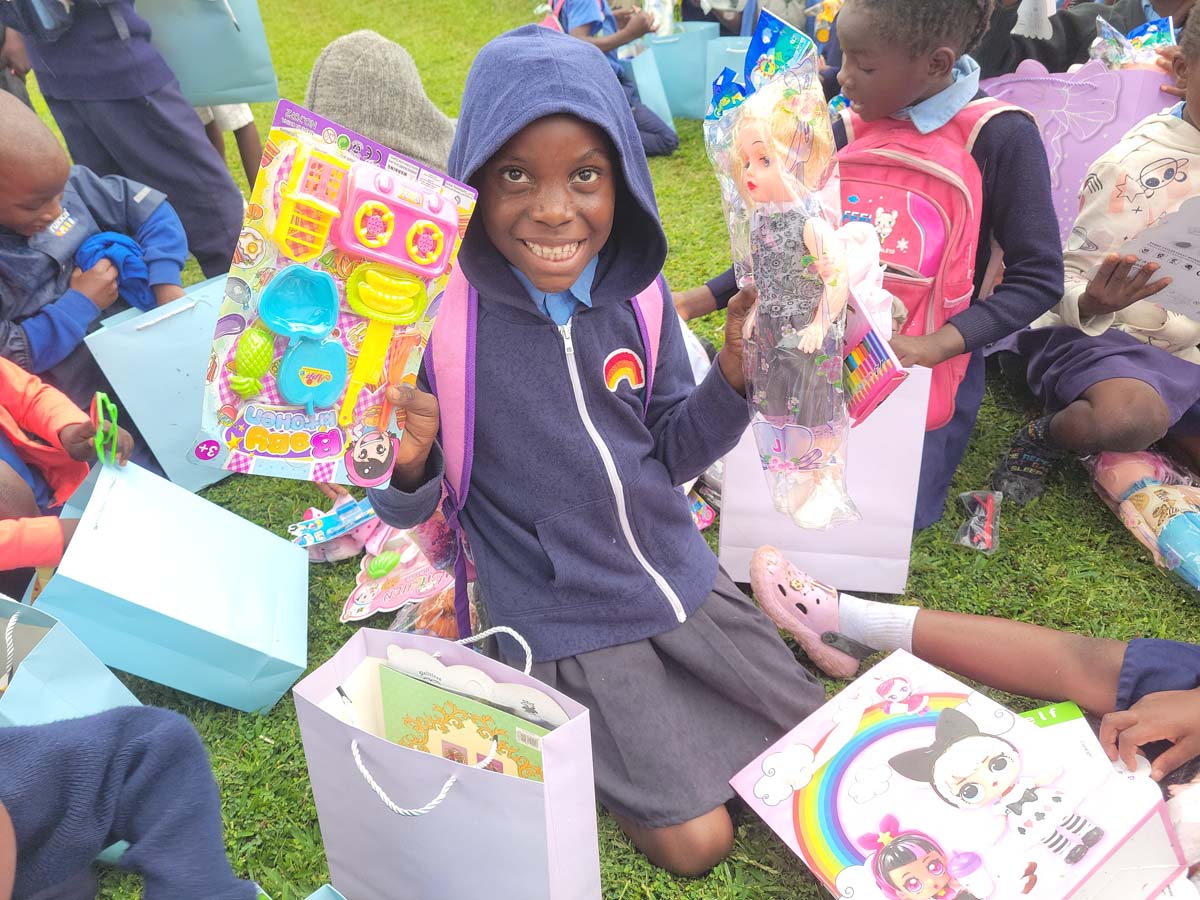 Child holding up toys and smiling