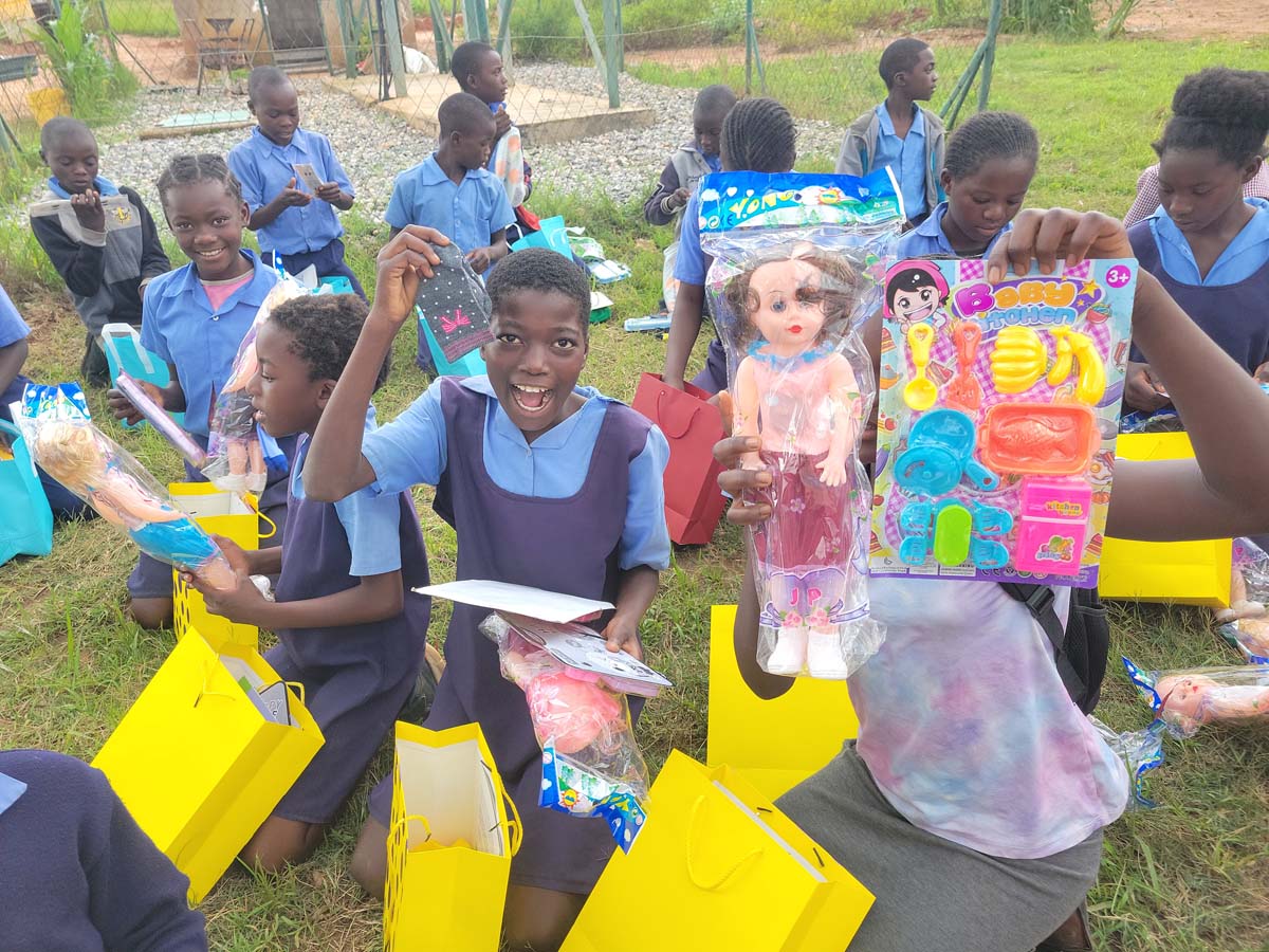Children holding gifts and toys, smiling at the camera