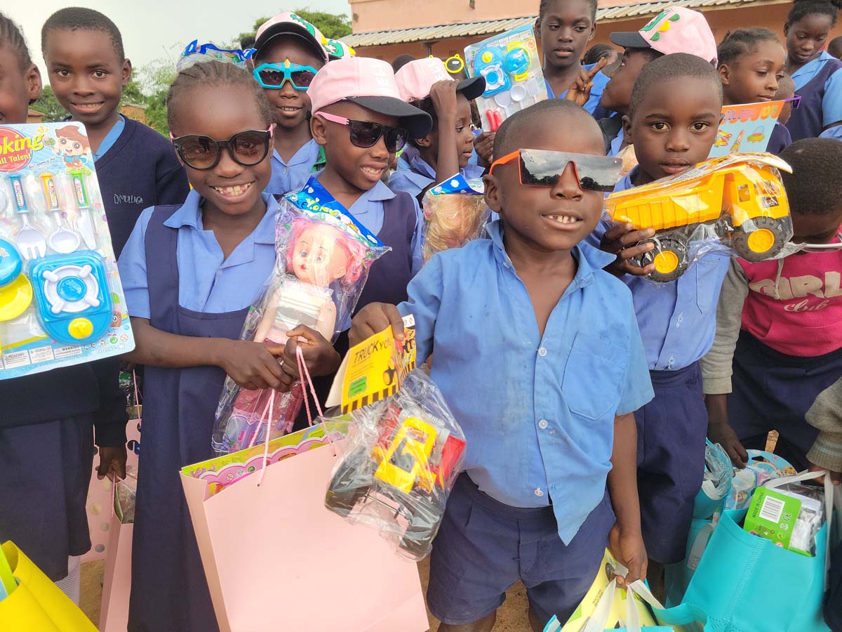 A group of children holding gifts and toys, smiling at the camera