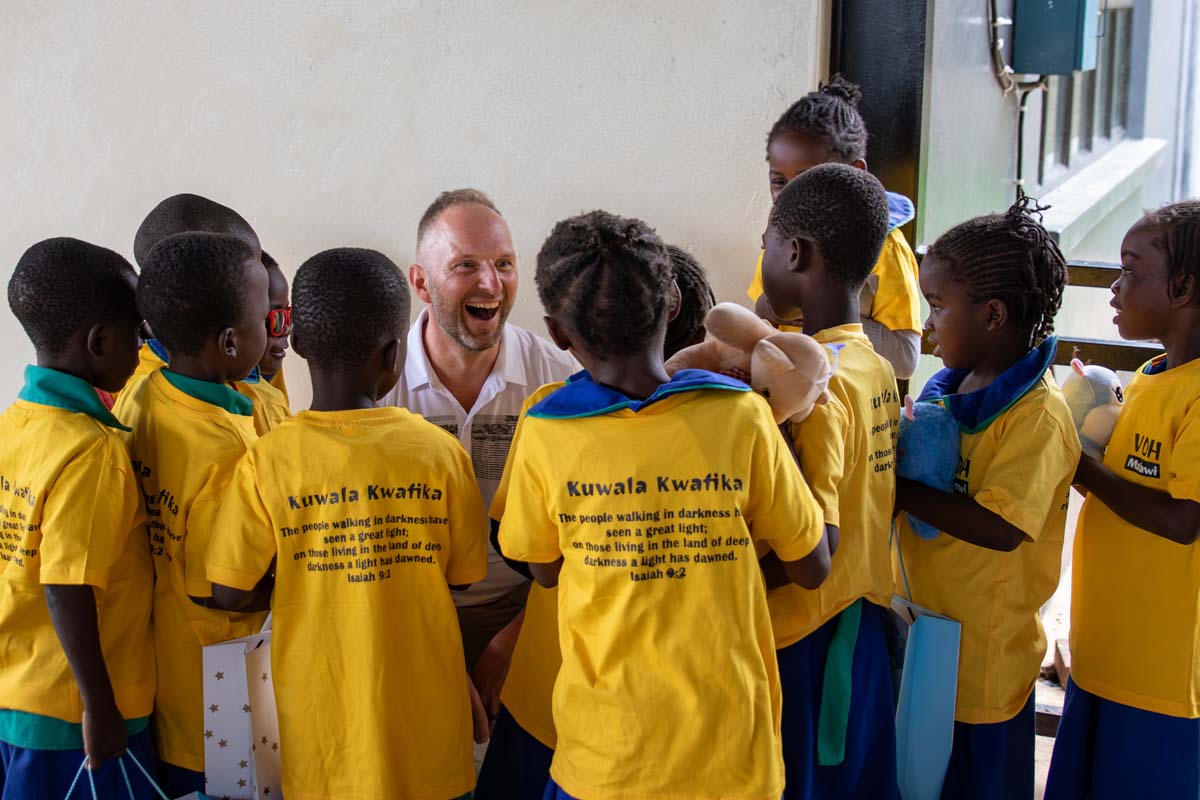 Group of kids holding toys talking to an adult who is smiling