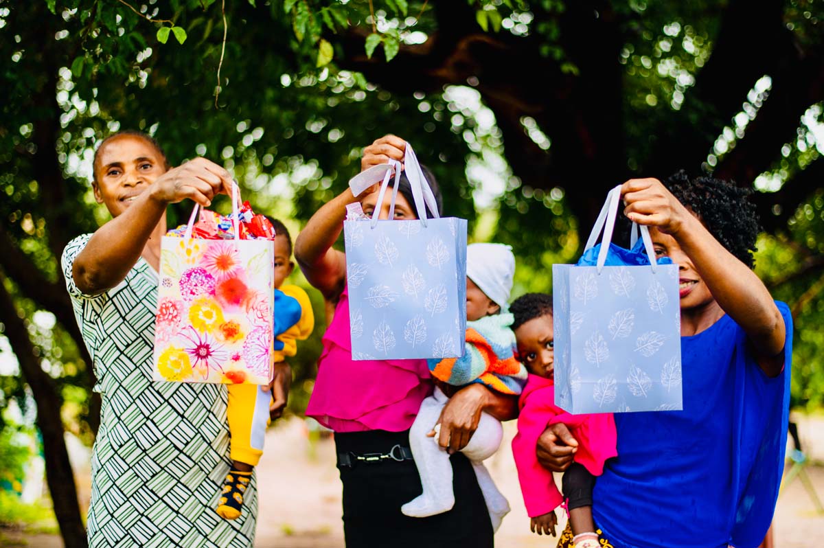 Three adults each holding a baby and a Hope Pack gift bag