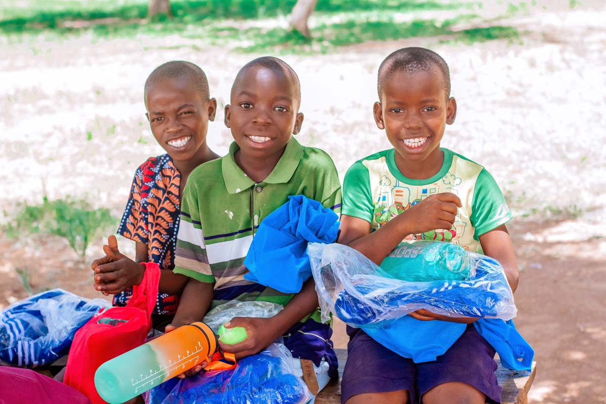 Three children holding their gifts and smiling at the camera