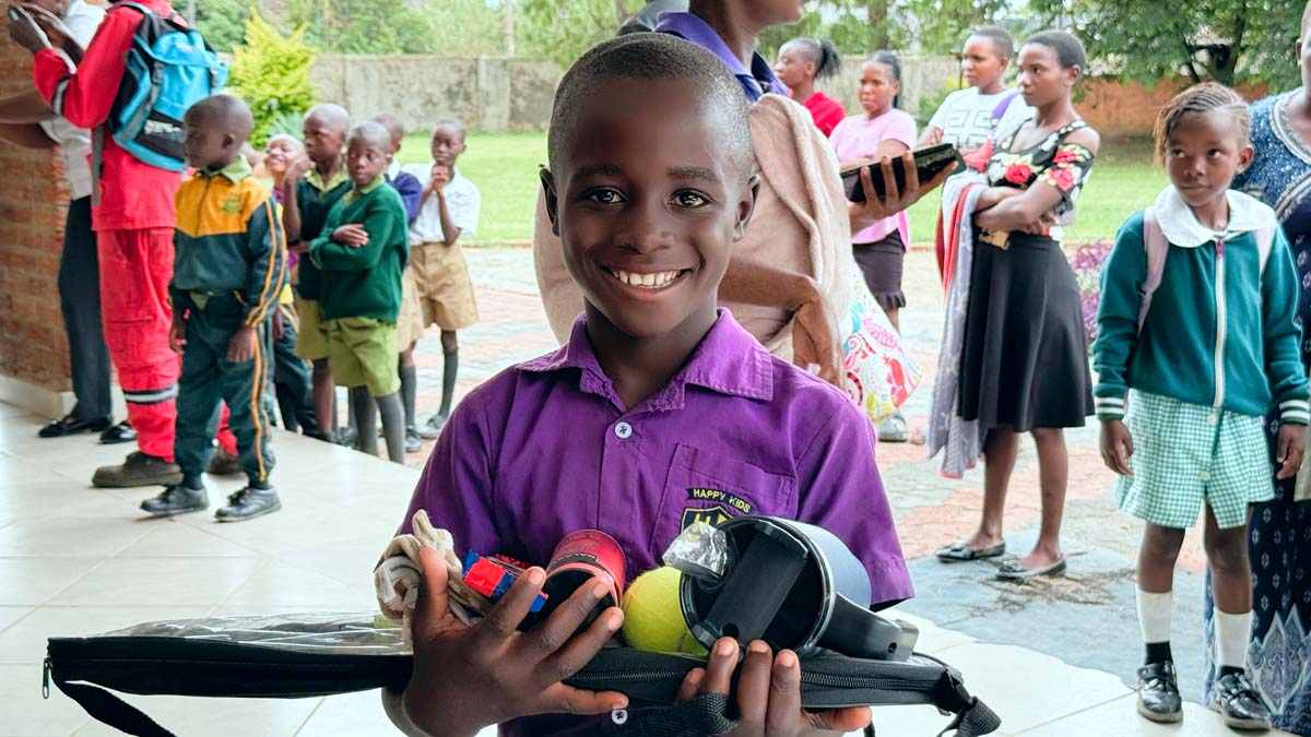 Child holding up gifts and smiling at camera