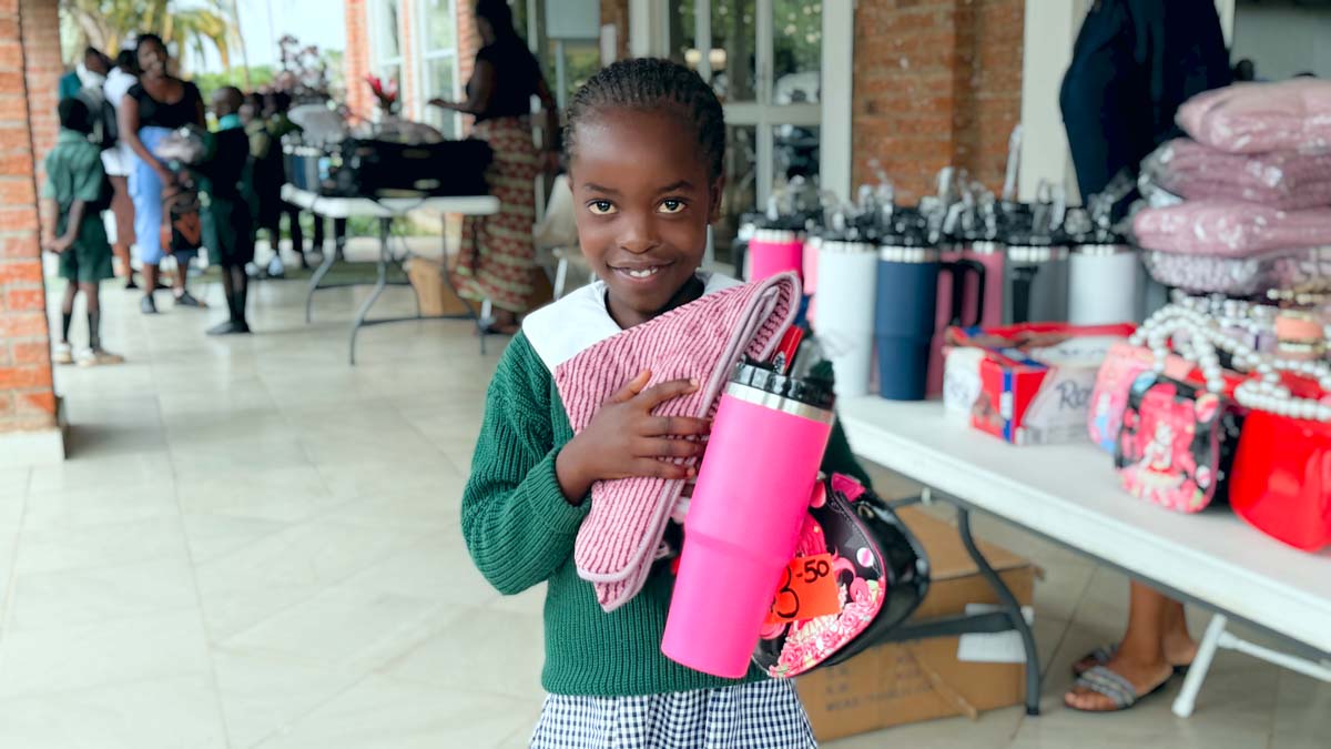 Child holding up gifts and smiling at camera
